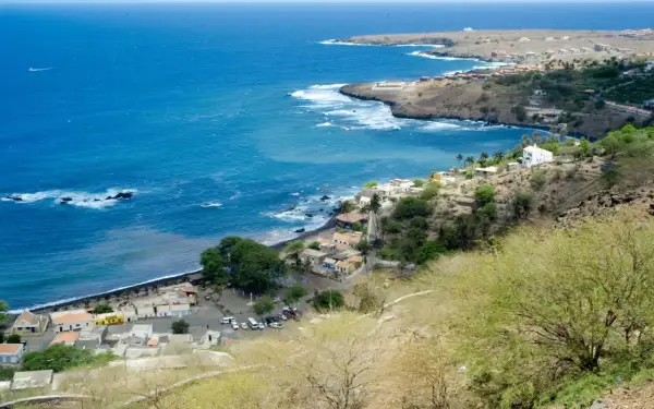 Vue d'un village côtier au Cap-Vert, avec des maisons blanches et colorées nichées sur une colline. Le nom de famille cap verdien résonne dans l'air salin.